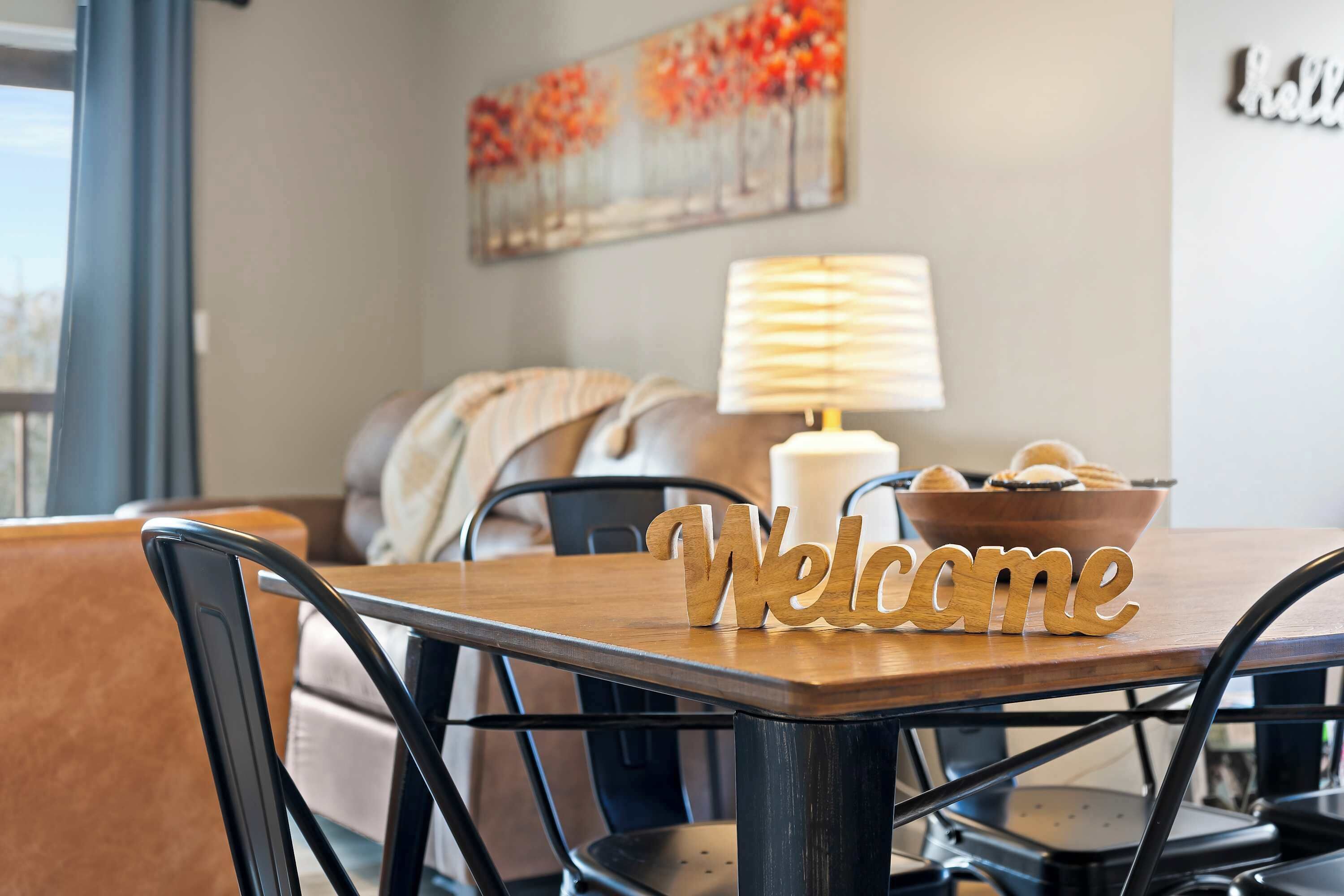 Une table à manger avec une pancarte « Bienvenue », un panier de pain et une lampe.