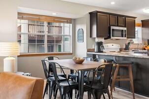 Una cocina moderna con armarios oscuros, un microondas y un comedor con mesa y sillas.