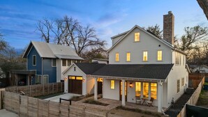 Une maison à deux étages avec un garage, une véranda et une cour clôturée.