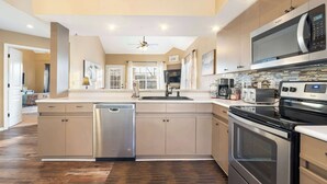 A modern kitchen with a dishwasher, oven, microwave, and a large island with a sink.