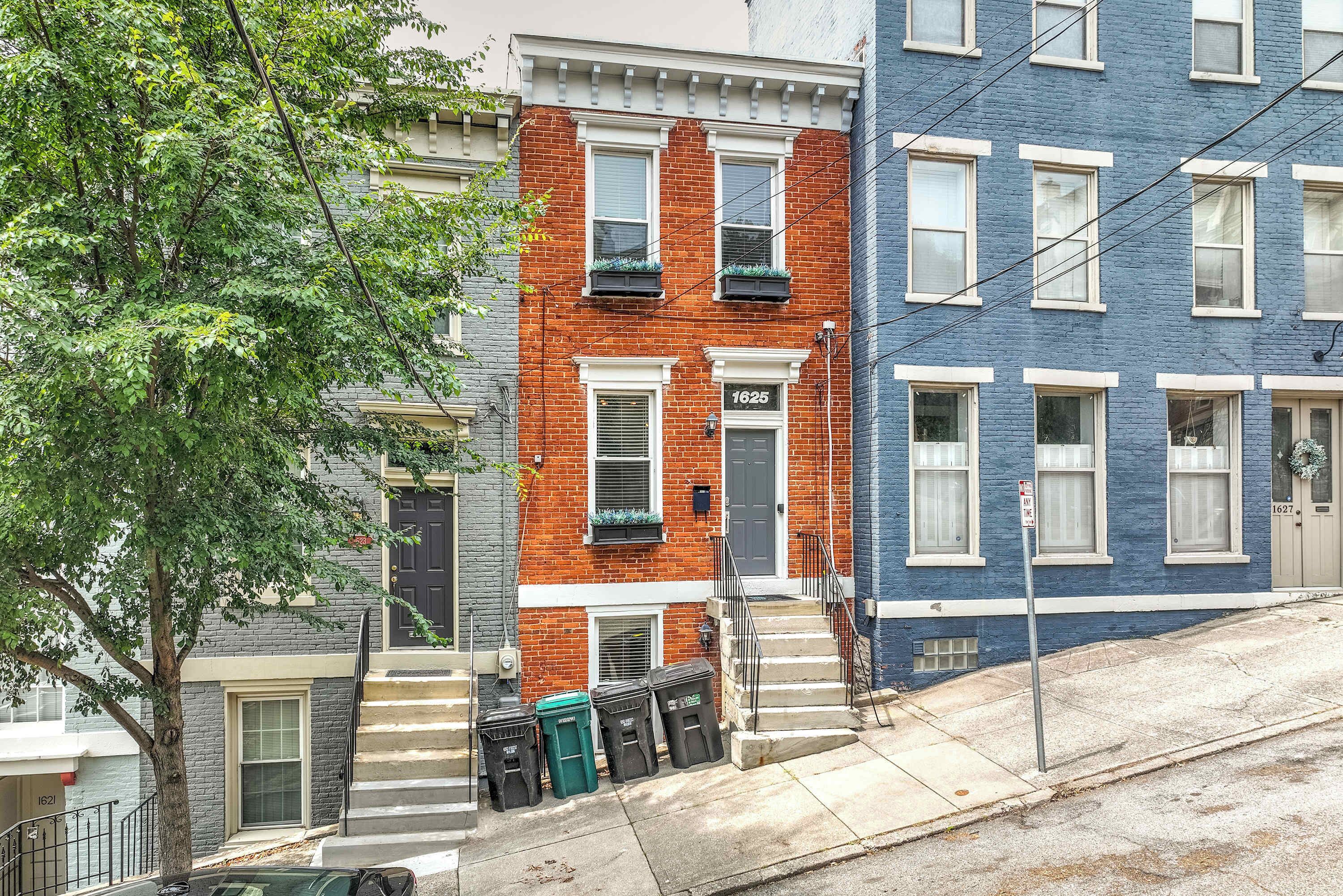 A row of townhouses with a brick facade, a blue painted exterior, and a tree in the foreground.
