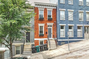 A row of townhouses with a brick facade, a blue painted exterior, and a tree in the foreground. - 2 King Beds Near OTR + Downtown Free Parking (Cincinnati)
