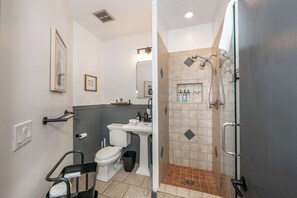 A bathroom with a toilet, sink, shower, and a wheelchair-accessible bench. - 2 King Beds Near OTR + Downtown Free Parking (Cincinnati)