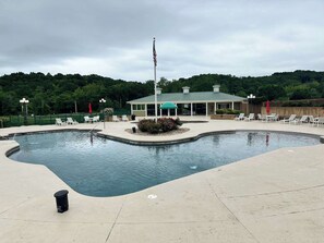 Une piscine avec des chaises longues, un patio couvert et un mât pour drapeau.