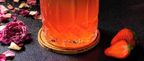 A cocktail glass with a strawberry garnish on a coaster.