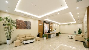 A modern hotel lobby with a reception desk, seating area, and potted plants. - Love St Hotel (Hanoi)