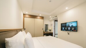 A hotel room with a bed, a TV mounted on the wall, and a wooden headboard. - Love St Hotel (Hanoi)