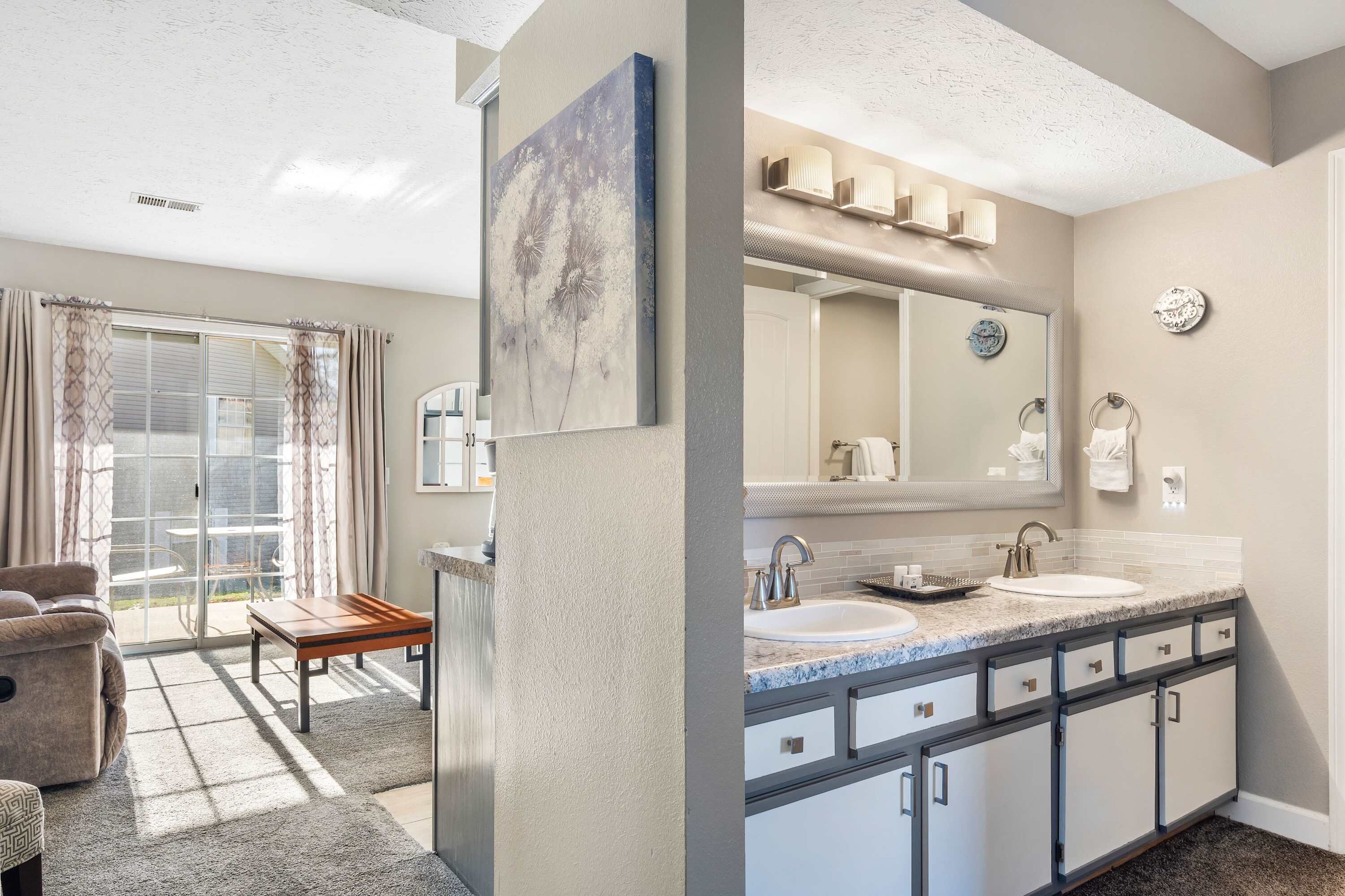 A modern bathroom with a large mirror, two sinks, and a shower area.