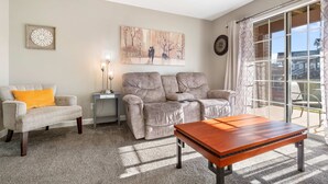 A living room with a beige sofa, a patterned armchair, a wooden coffee table, and a painting on the wall. - Windsor Cottage Fall Creek Beauty by Table Rock! (Branson)