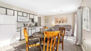 A modern kitchen with white appliances, a dining area with a wooden table and chairs, and a living room with a sofa and a painting. - Windsor Cottage Fall Creek Beauty by Table Rock! (Branson)