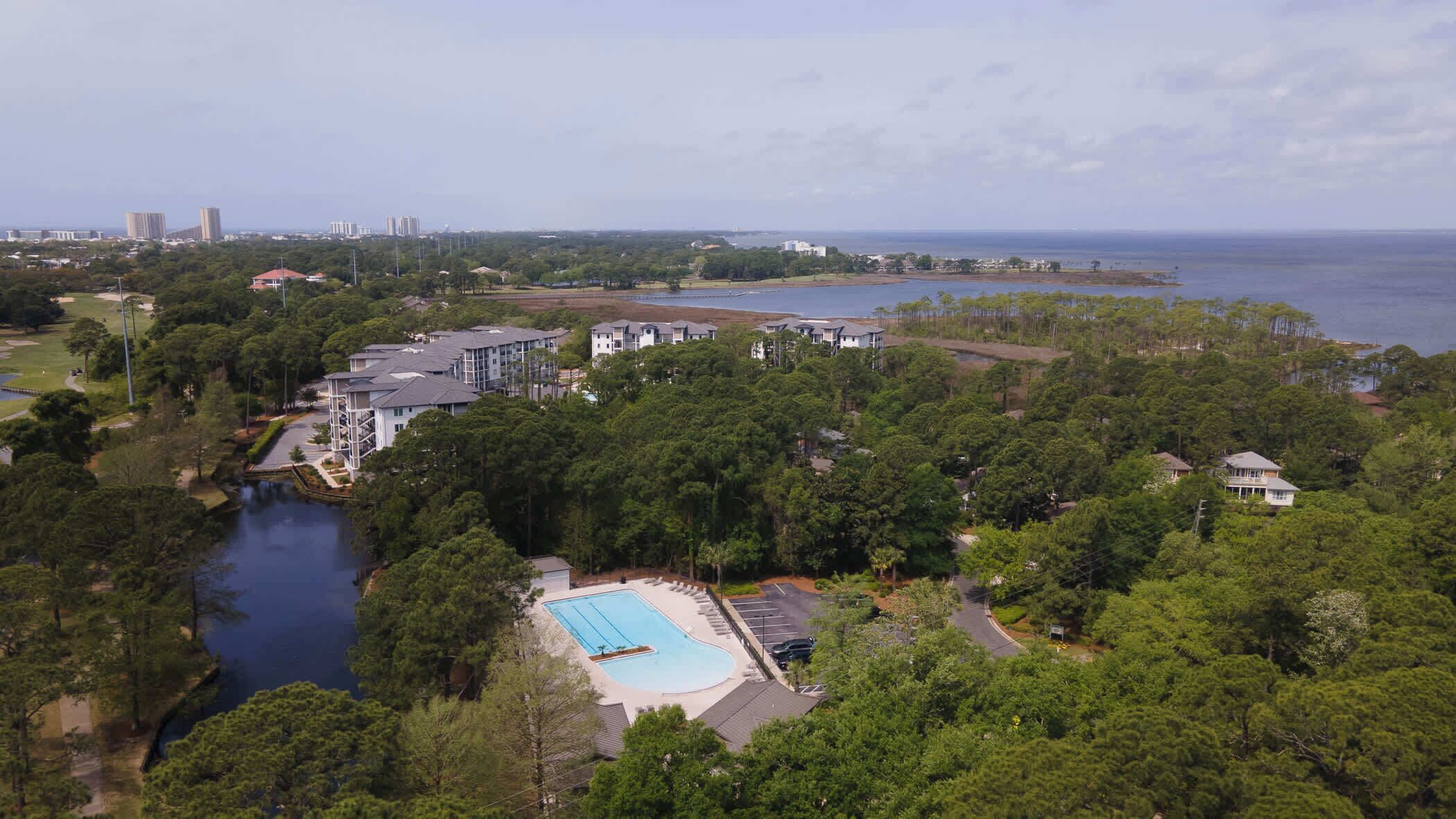 Et resort med swimmingpool, omgivet af frodig vegetation og havudsigt.