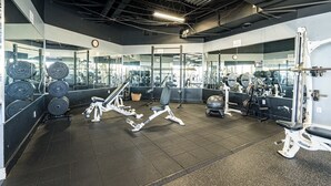 A gym with various exercise equipment, mirrors, and weight racks. - Seashell Shuffle at Pilot House (Miramar Beach)