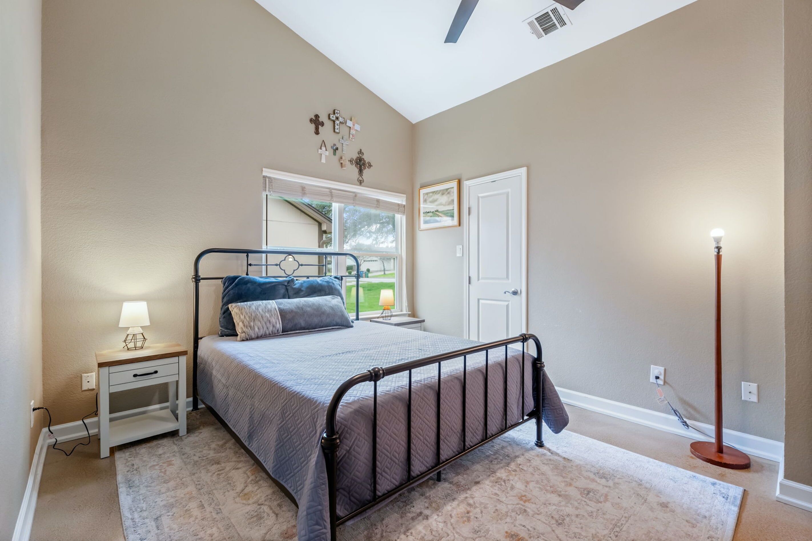 A bedroom with a bed, nightstand, lamp, and a floor lamp.