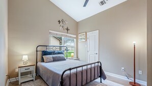 Un dormitorio con cama, mesita de noche, lámpara y lámpara de pie.
