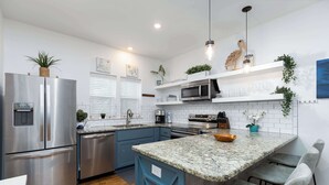 Una cocina moderna con electrodomésticos de acero inoxidable, una isla con encimera de granito y armarios azules.