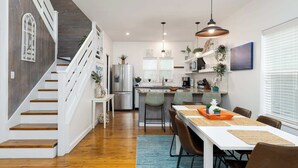 Una cocina moderna con una isla central, muebles blancos y electrodomésticos de acero inoxidable.