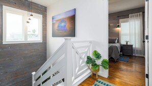Una escalera con detalles de madera, una barandilla blanca y un cuadro de una medusa en la pared.