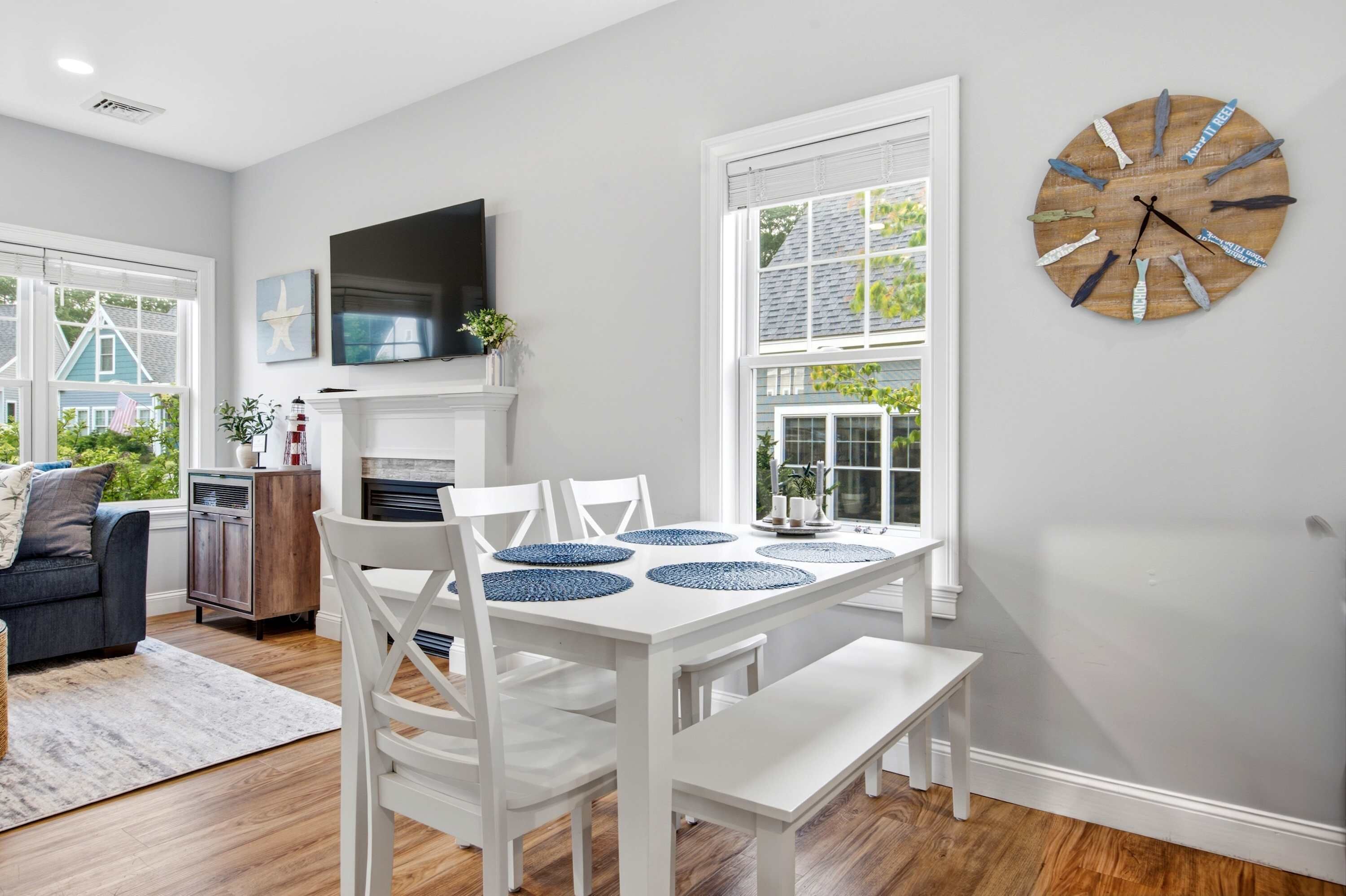 A dining area with a white table, blue placemats, and white chairs.