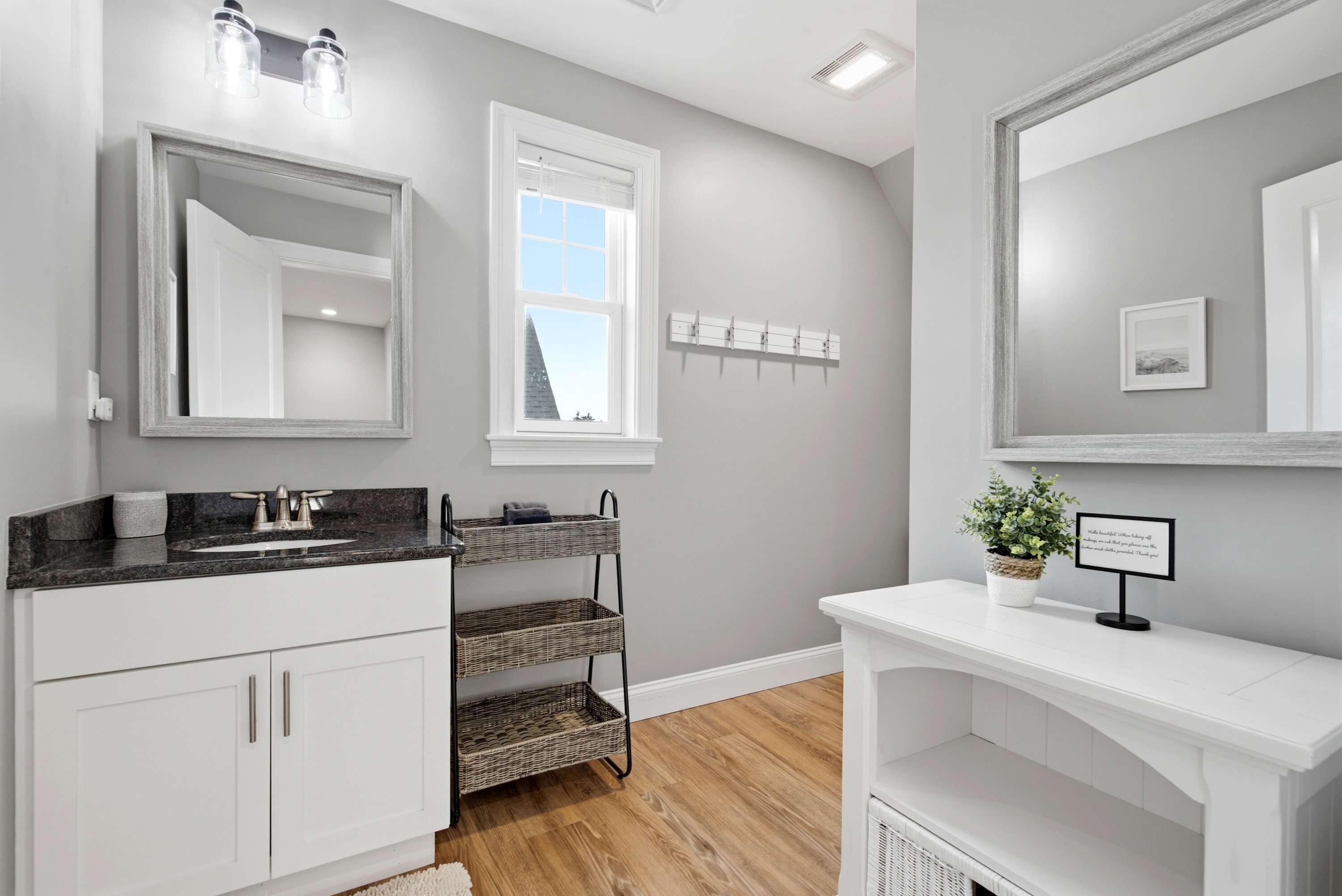 A modern bathroom with a vanity, a mirror, a window, and a wall-mounted towel rack.