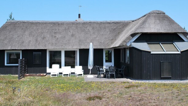 A building with a thatched roof and a modern extension with large windows. There are outdoor seating areas with tables and chairs. - "Kastehelmi" - 400m from the sea by Interhome (Blåvand)