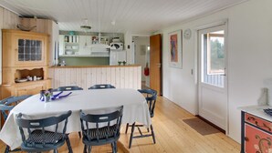 A dining area with a white table and chairs, a wooden cabinet, and a kitchen in the background. - "Kastehelmi" - 400m from the sea by Interhome (Blåvand)