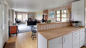 A spacious kitchen with wooden cabinets, a coffee machine, and a dining area with chairs and a table. - "Kastehelmi" - 400m from the sea by Interhome (Blåvand)