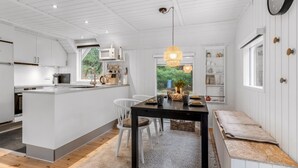Una cocina moderna con armarios blancos, una isla central y una zona de comedor con mesa y sillas.