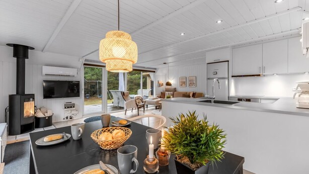 Una cocina moderna con una isla central, electrodom ésticos integrados y un amplio ventanal con vistas a un jardín.