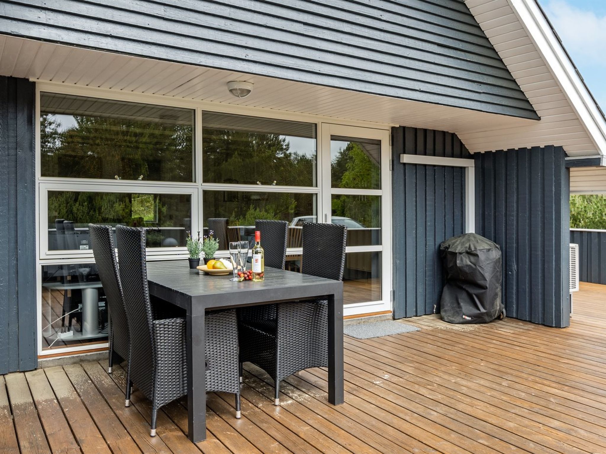 An outdoor deck with a table and chairs, a grill, and a barbecue grill.
