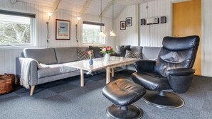 A cozy room with a grey sofa, a black leather chair, and a small table with a vase of flowers. - "Emmi" - 2.5km from the sea by Interhome (Blåvand)