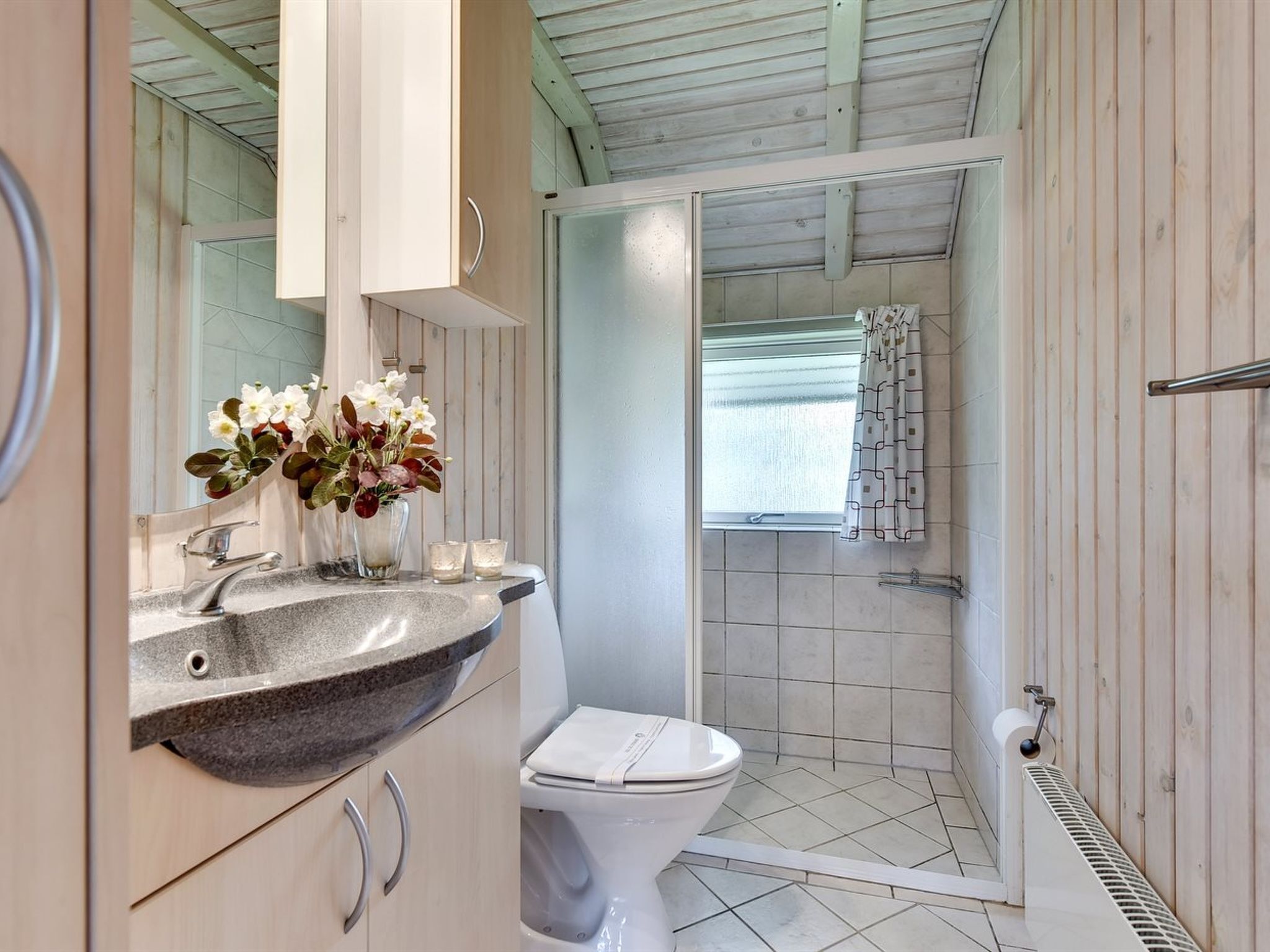 Une salle de bain avec des toilettes blanches, un lavabo en granit et un espace douche.