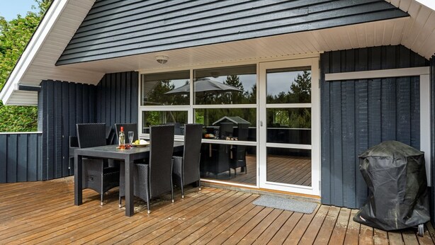 A covered outdoor patio with a table and chairs, a grill, and a sliding glass door leading to a deck. - "Emmi" - 2.5km from the sea by Interhome (Blåvand)