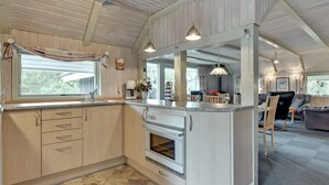 A modern kitchen with a built-in oven, a dining area with a table and chairs, and a living room with a sofa and a coffee table. - "Emmi" - 2.5km from the sea by Interhome (Blåvand)
