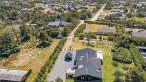 Vue aérienne d’un quartier résidentiel avec des maisons, une route et un grand bâtiment doté d’un toit en pente.