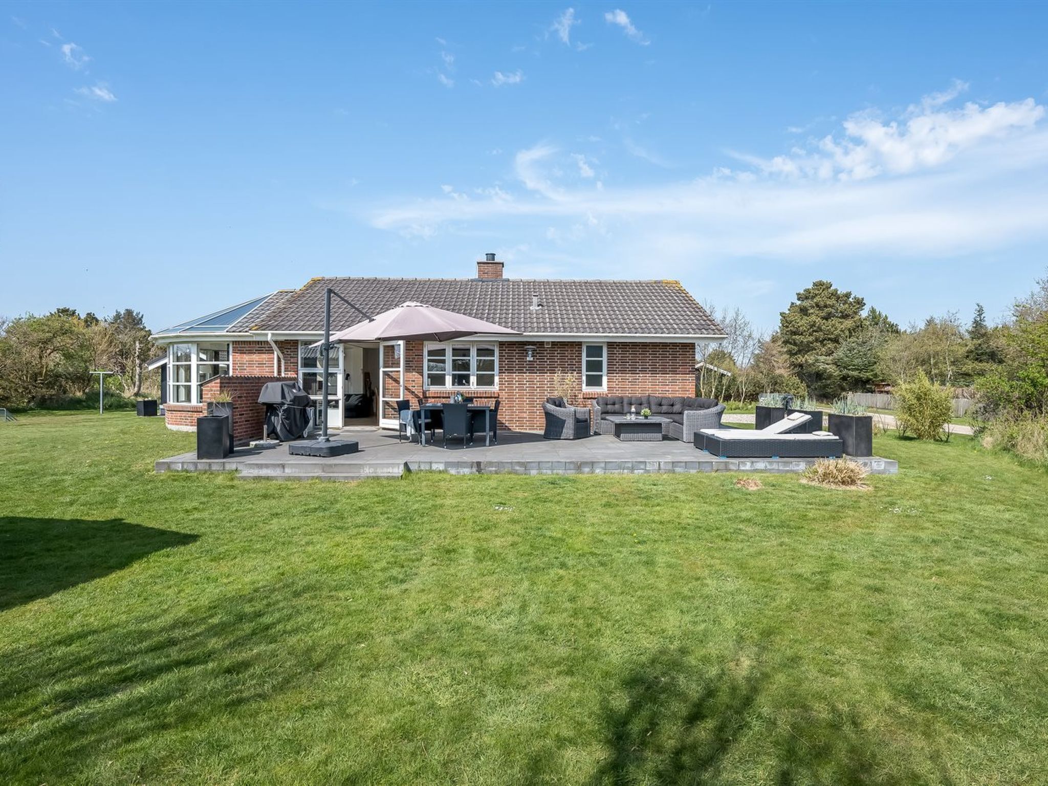 Une maison avec un patio, du mobilier d’extérieur et un ciel dégagé.