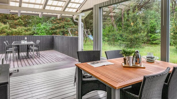 A covered patio with a table and chairs, a wooden deck, and a view of a garden. - "Tala" - 4km from the sea by Interhome (Blåvand)