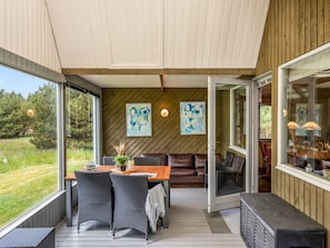 A covered outdoor dining area with a table, chairs, and a bench.