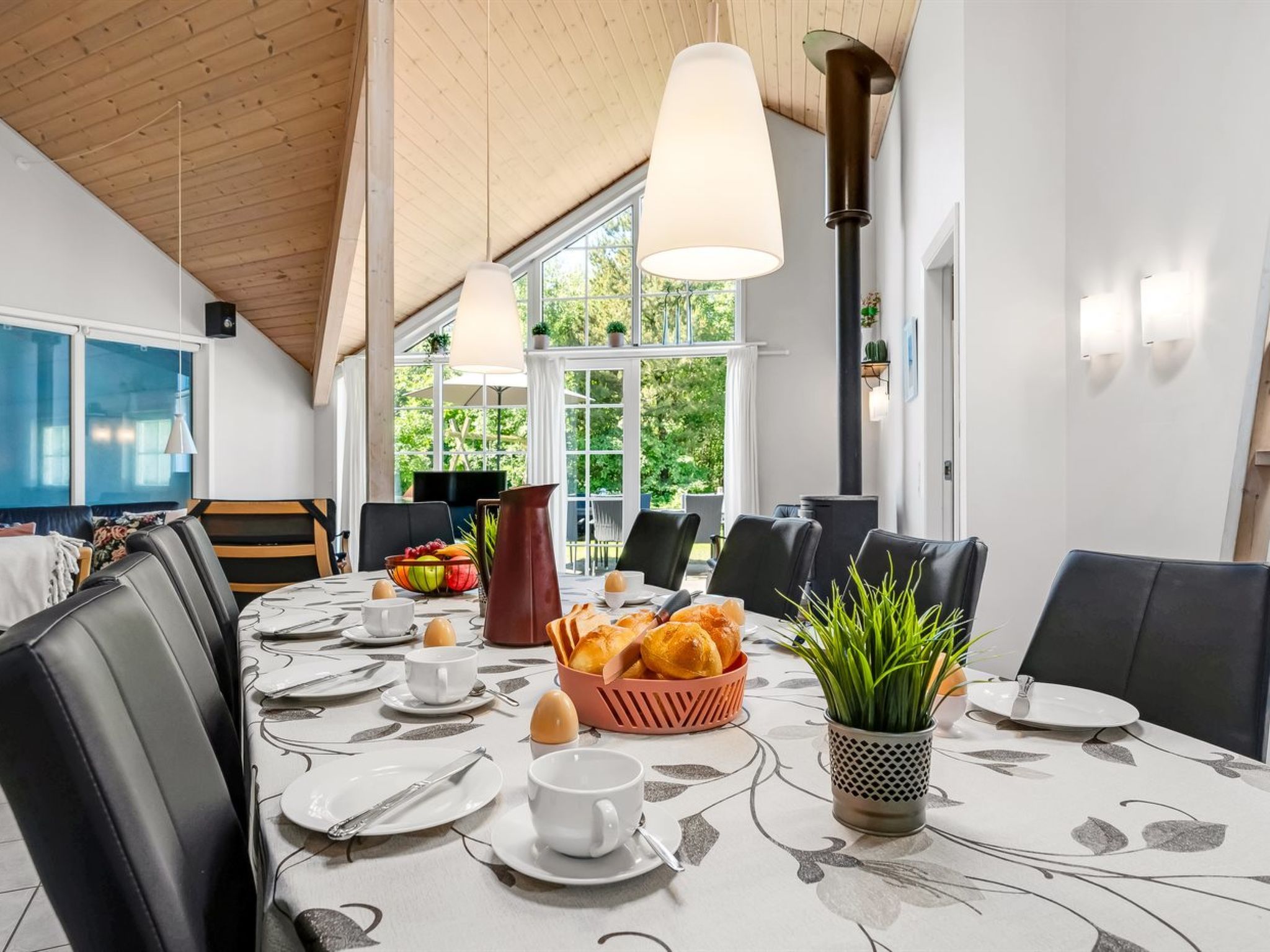 A dining area with a table set for breakfast, including bread, eggs, and fruit.
