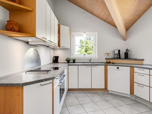 Eine moderne Küche mit weißen Schränken, Holzboden und einem Fenster, das für natürliches Licht sorgt.