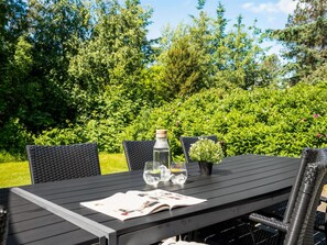 An outdoor table set with chairs, a bottle, glasses, and a small potted plant. - "Femmy" - 600m from the sea by Interhome (Blåvand)