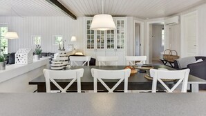 A modern dining area with a central table, white chairs, and a hanging light fixture. - "Raili" - 1.5km from the sea by Interhome (Blåvand)