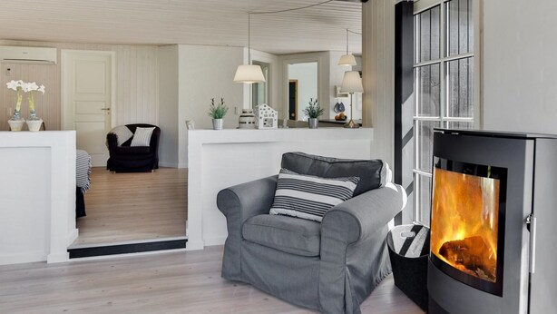 A modern living room with a fireplace, a grey sofa, a black armchair, and a wooden floor. - "Raili" - 1.5km from the sea by Interhome (Blåvand)