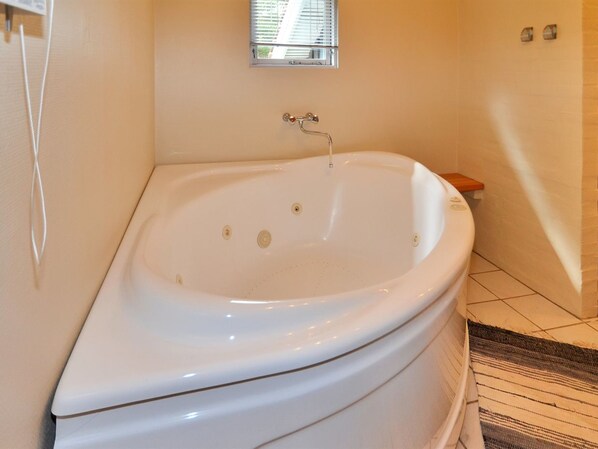 A bathroom with a freestanding bathtub, a small window, and a tiled floor.