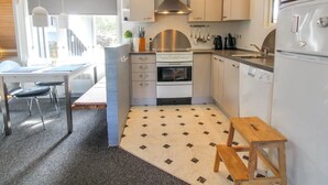 A modern kitchen with a central island, a dining area with a table and chairs, and a small wooden stool.