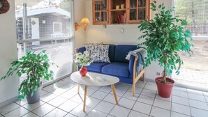 A living room with a blue sofa, a wooden cabinet, and two potted plants.