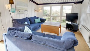 Ein gemütliches Wohnzimmer mit einem blauen Sofa, einem Holztisch und einem Fernseher.