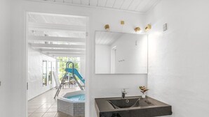 A bathroom with a black sink, a mirror, and a view of a pool and slide area. - "Joseline" - 1.8km from the sea by Interhome (Blåvand)