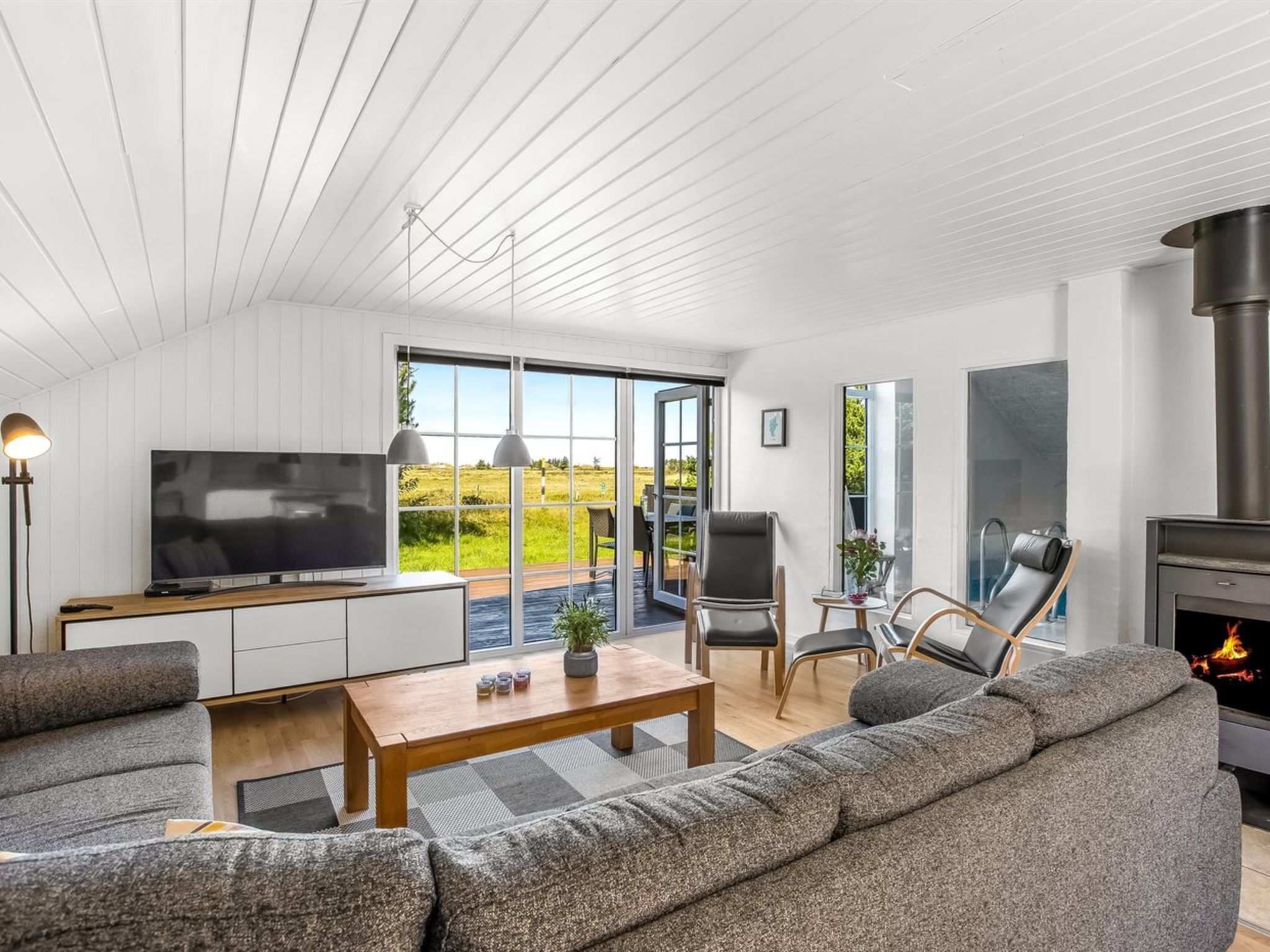 A modern living room with a TV, sofa, and fireplace.