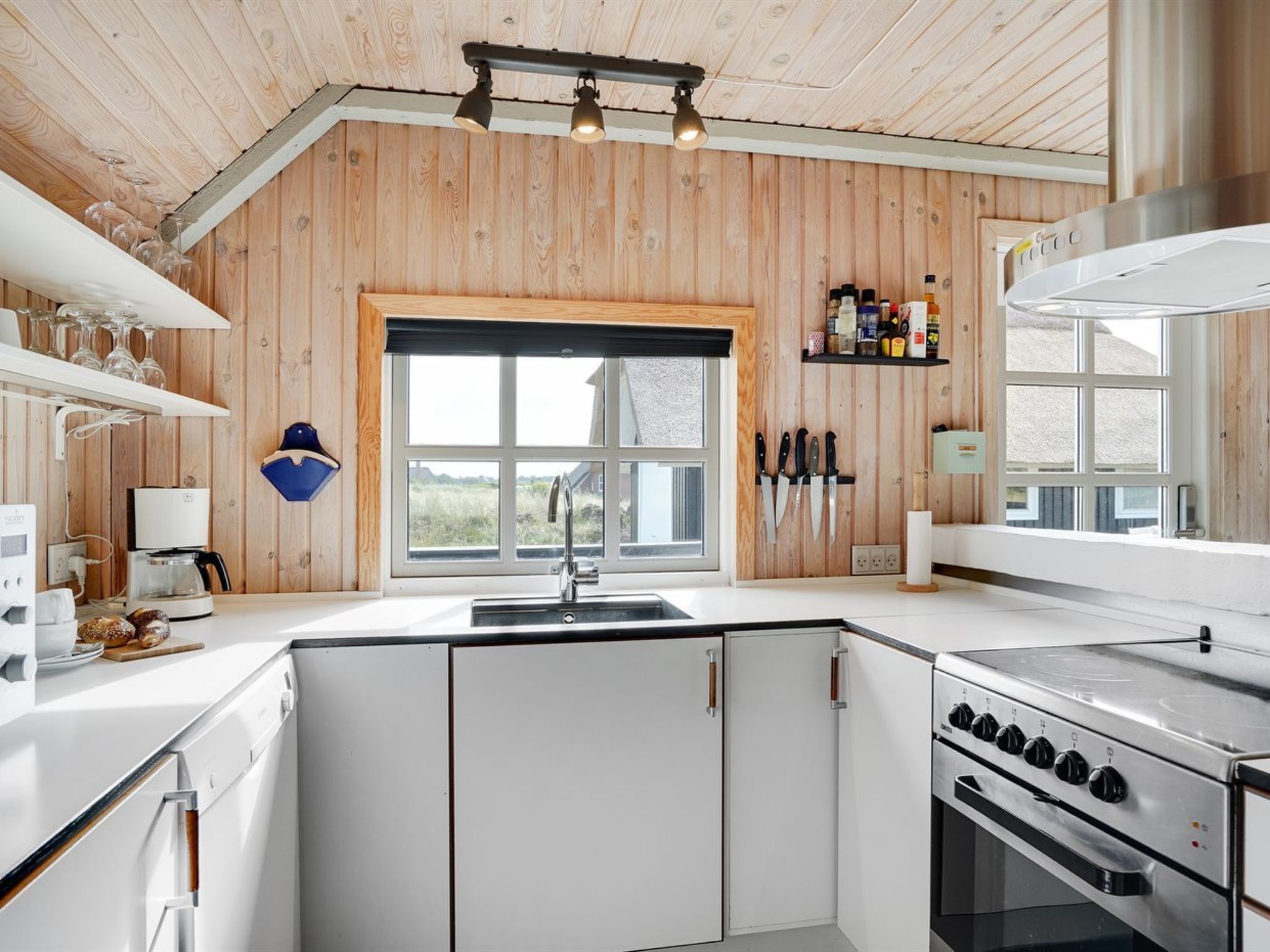 Une cuisine moderne avec des murs en bois, une grande fenêtre et un poêle.