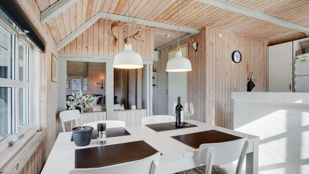 Una cocina moderna con armarios blancos, techo de madera e iluminación colgante.